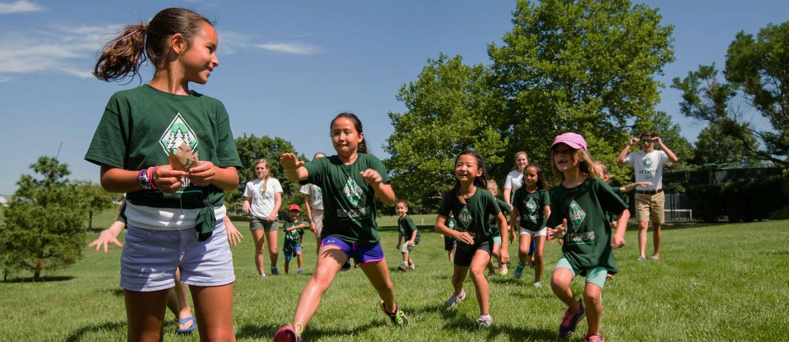 Campers in KE Camps shirts running across a club lawn